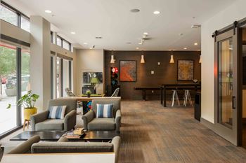 A modern waiting room with grey couches and a wooden floor.
